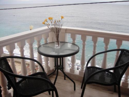 a table with chairs and a vase with flowers on a balcony at Antonios Rooms in Akrata