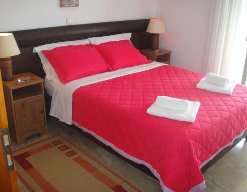 a large red bed with two pillows on it at Antonios Rooms in Akrata