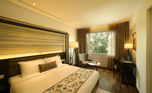 a hotel room with a bed and a desk and a window at The Royale Senate Race Course, Bangalore in Bangalore
