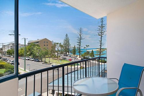 a patio area with chairs, a table, and a balcony at BreakFree Grand Pacific in Caloundra