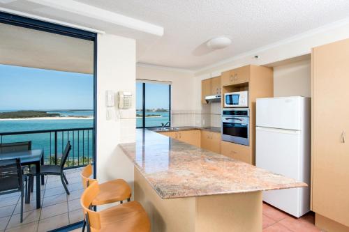 a kitchen and dining room with a view of the ocean at BreakFree Grand Pacific in Caloundra