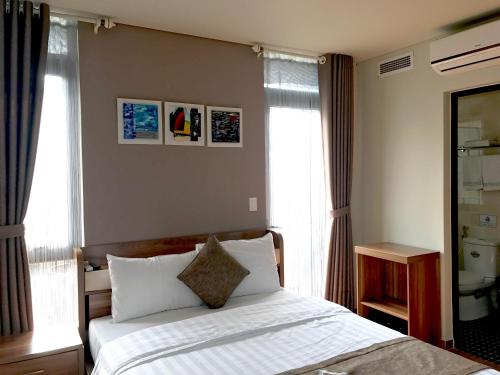 a bedroom with a bed with white sheets and windows at F & F Hotel in Hai Phong