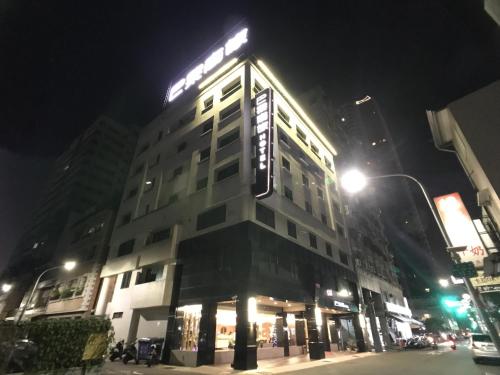 高雄的住宿－巴黎商務酒店，一座建筑物,晚上在建筑物的一侧有标志