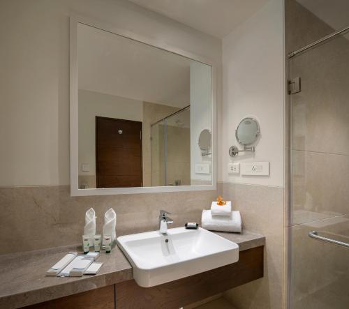 a bathroom with a sink and a mirror and a shower at Kabir Hotel & Spa in Vadodara