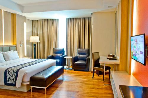 a hotel room with a bed and a desk and chairs at Nagoya Hill Hotel Batam in Nagoya