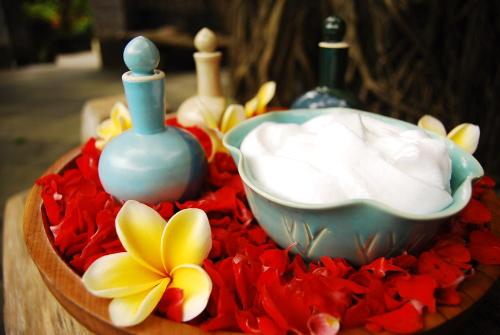 a bowl of whipped cream and a bowl of flowers at Hotel Puri Bambu in Jimbaran