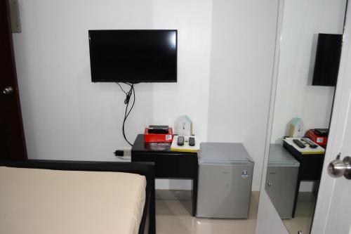 a room with a bed and a tv on a wall at Sergi's Resort and Hotel in Palompon