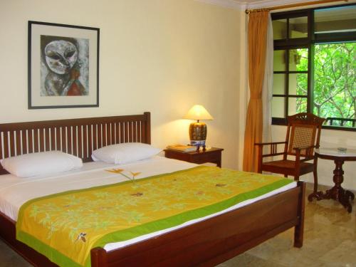 a bedroom with a bed and a table and a window at Hotel Puri Bambu in Jimbaran