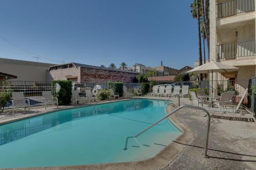 a large swimming pool with chairs and an umbrella at Vagabond Inn Glendale in Glendale