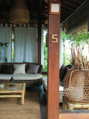 a porch with a couch and chairs and a sign at Tanjungan in Gili Gede