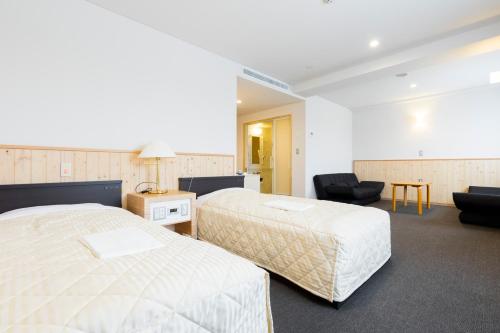 a hotel room with two beds and a chair at Hotel Higashimokoto in Abashiri