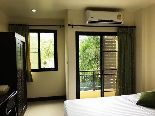 a bedroom with a bed and two windows and a balcony at T.P. Place Hotel in Phangnga