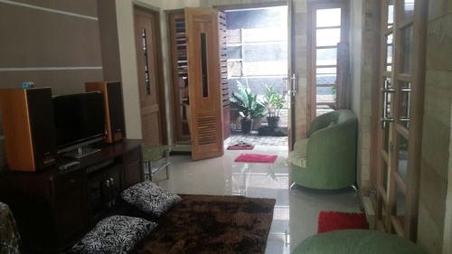 a living room with a television and a green chair at Homestay Syariah Grahadi in Malang