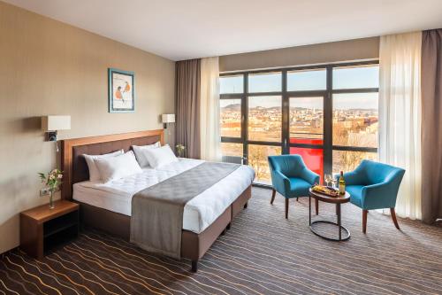 ein Hotelzimmer mit einem Bett und zwei blauen Stühlen in der Unterkunft Taurus City Hotel in Lwiw