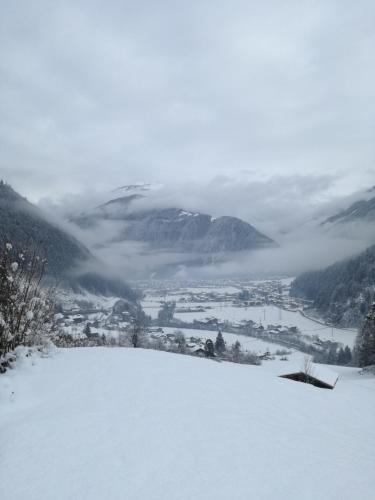 a snow covered hill with a city in the distance at Haus Mühlbichl in Finkenberg