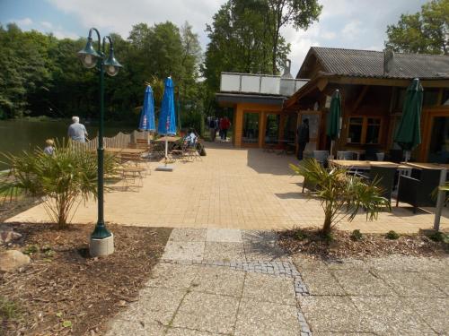 a patio with tables and blue umbrellas and a building at Angelhof Weseloh in Karolei