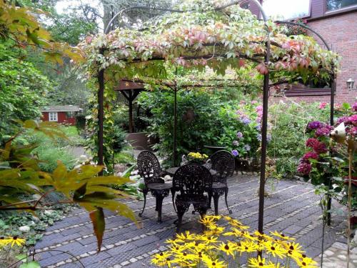 a garden with a pergola with chairs and flowers at Haus am See in Schiffdorf