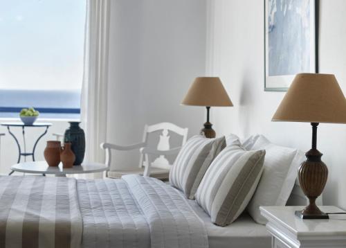 a white bedroom with a bed with pillows and lamps at San Marco Hotel and Villas in Houlakia