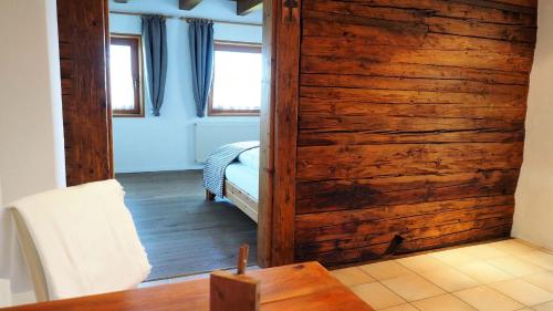 a room with a wooden wall with a bed and a table at Bergh AM BERG in Irschen