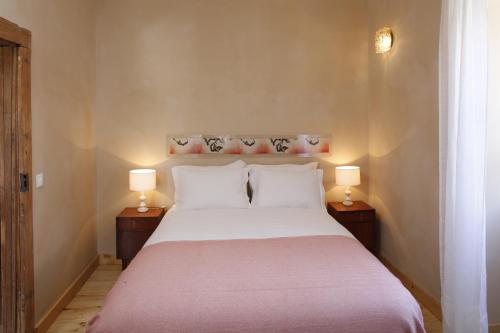 una camera da letto con un grande letto bianco con due lampade di Casa Estrela a Juncais