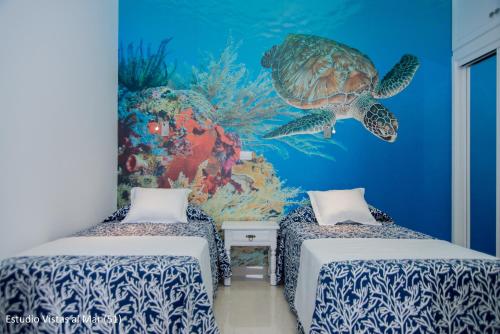 Habitación con 2 camas y un mural de tortugas marinas en Apartamentos Juan Pérez- Viviendas Vacacionales, en Las Palmas de Gran Canaria