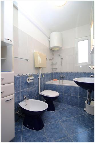 a bathroom with two toilets and a sink and a tub at Apartments HULJEV in Primošten