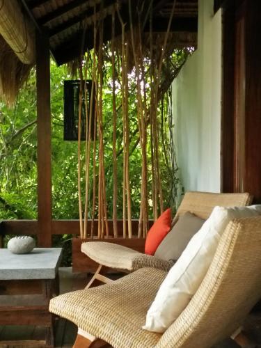 a porch with a couch and chairs and trees at Tanjungan in Gili Gede