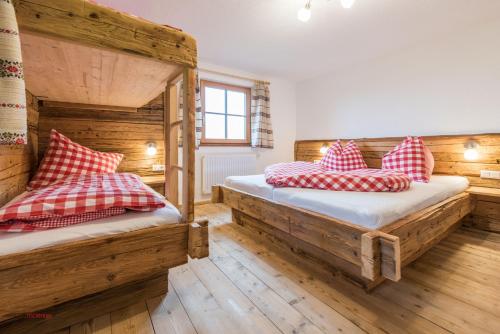 two beds in a room with wooden walls and wooden floors at Almliesl PIES-533 in Piesendorf