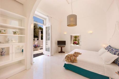 Un dormitorio blanco con una cama y un televisor. en Villa Silvana Relais, en Sorrento