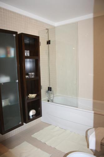 een badkamer met een bad en een glazen douche bij Sesimbra Mar Apartamento in Sesimbra