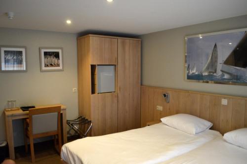a bedroom with two beds and a cabinet and a desk at Hotel Honfleur in Middelkerke