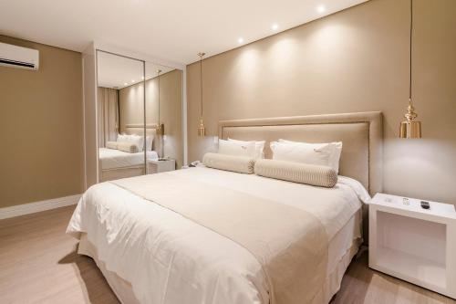 a bedroom with a large white bed and a mirror at Araçatuba Plaza Hotel in Araçatuba