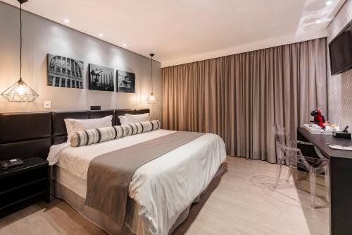 a hotel room with a large bed and a desk at Araçatuba Plaza Hotel in Araçatuba
