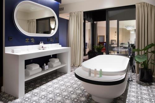 a bathroom with a tub and a toilet and a mirror at Hôtel Cardinal Bordeaux Centre in Bordeaux