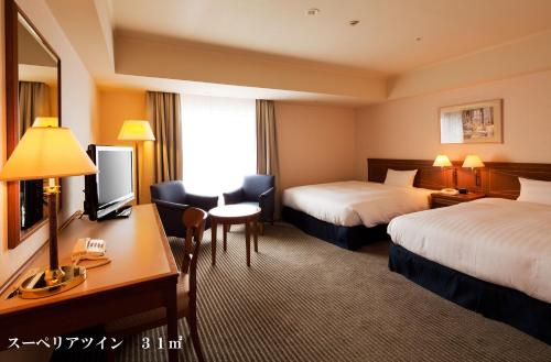a hotel room with two beds and a desk at HOTEL GRAND HILLS SHIZUOKA in Shizuoka