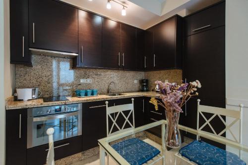a kitchen with black cabinets and a vase of flowers on a table at Bright and beautiful- VTV- Conde de Torrejón 10 in Seville