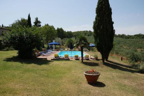 a pool in a yard with chairs and umbrellas at Podere Sagna in Castellina in Chianti