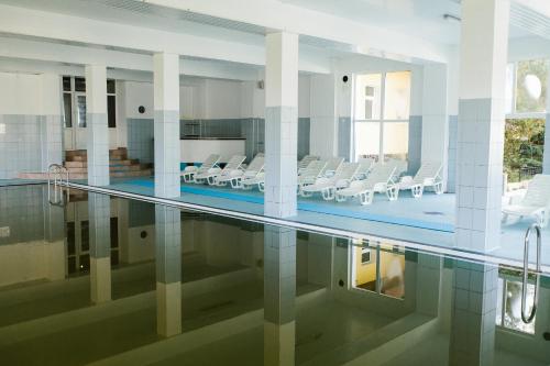 a pool with chairs and tables in a building at Hotel Dobsi in Bazna