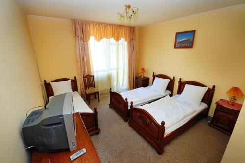 a bedroom with two beds and a tv in it at Chervona Gora in Mukacheve