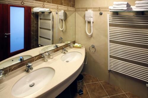 a bathroom with two sinks and a mirror and a shower at Hotel Savus in Slavonski Brod