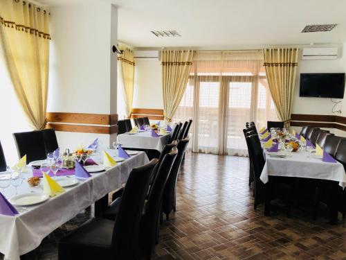 a dining room with two tables and black chairs at Pensiunea Ovidiu&Paula in Ibăneşti