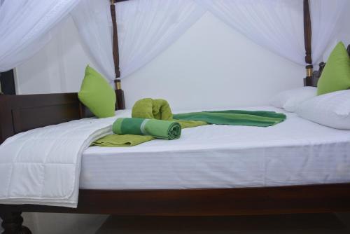 Bett mit grüner und weißer Bettwäsche und Kissen in der Unterkunft Star Nodes Villa in Galle