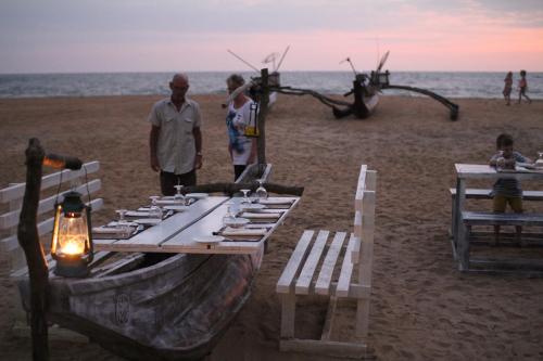 a picnic table on the beach with people on the beach at Star Nodes Villa in Galle