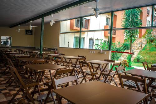 an empty restaurant with tables and chairs and windows at Pousada Vila Real Flats in Ouro Preto