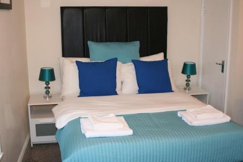 a bed with blue and white pillows and towels on it at ABBEY HOLIDAY ACCOMMODATiON in Whitby
