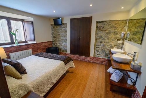 a bedroom with a large bed and a stone wall at Casona de Llanorrozo Apartamentos Rurales in Oviñana