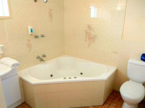 a bathroom with a tub and a toilet at Australia Park Motel in Albury