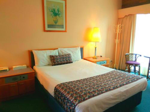 a hotel room with a large bed and a lamp at Australia Park Motel in Albury
