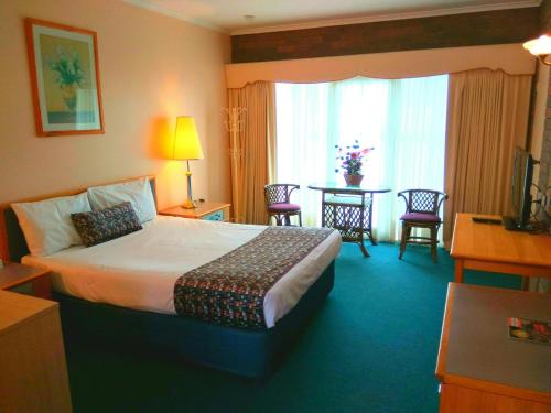 a hotel room with a bed and a table with chairs at Australia Park Motel in Albury