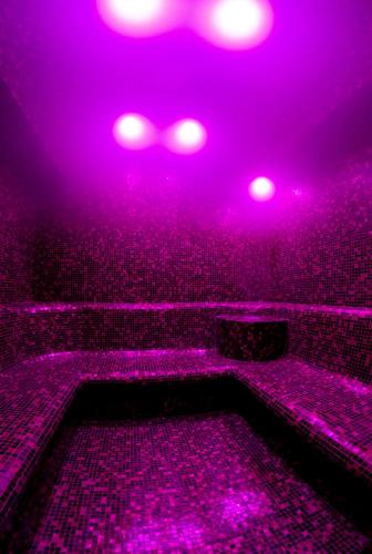a purple room with a tub with pink lights at Hotel Młyn Aqua Spa Biblioteka in Elblag